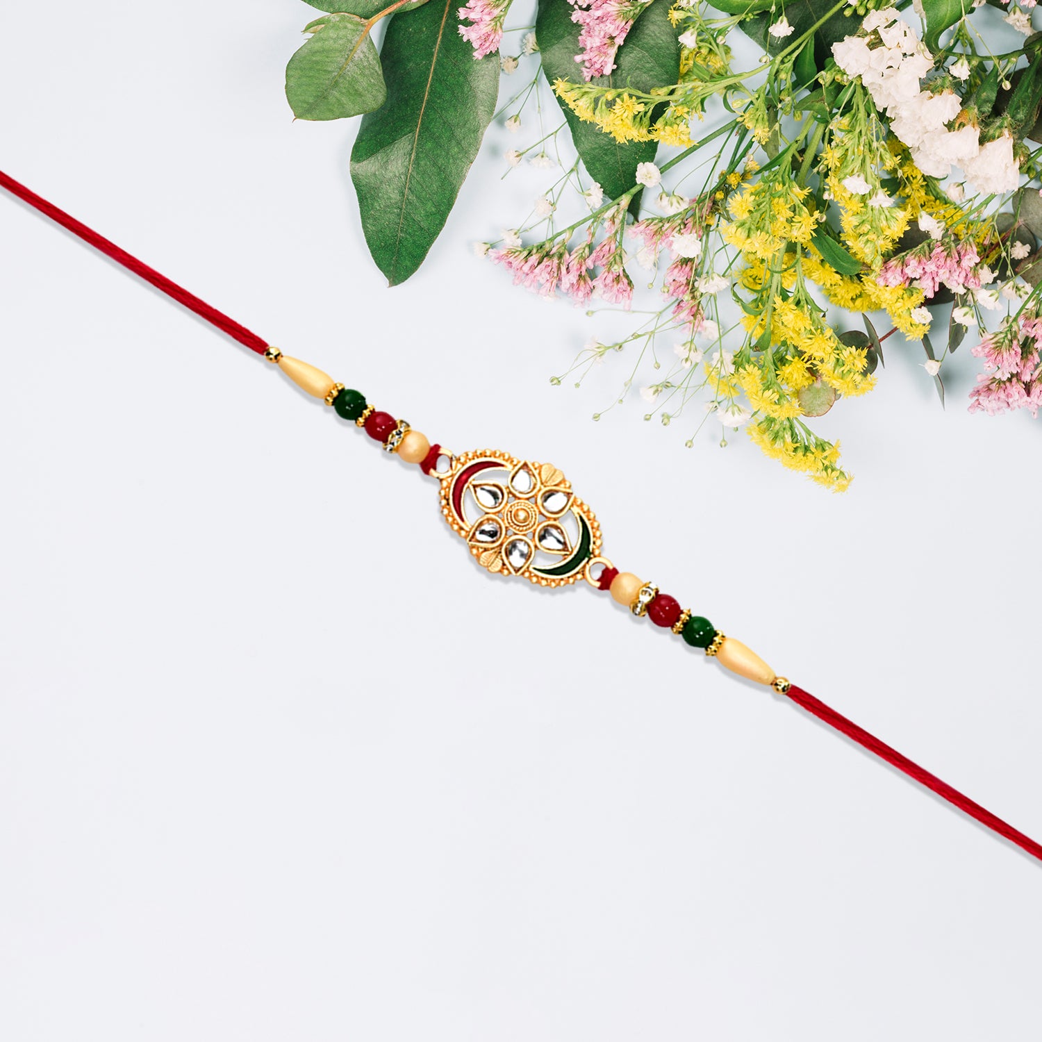 Traditional Oval Rakhi With Kundan Work And Red-green Beads Traditional Oval Rakhi With Kundan Work And Red-green Beads